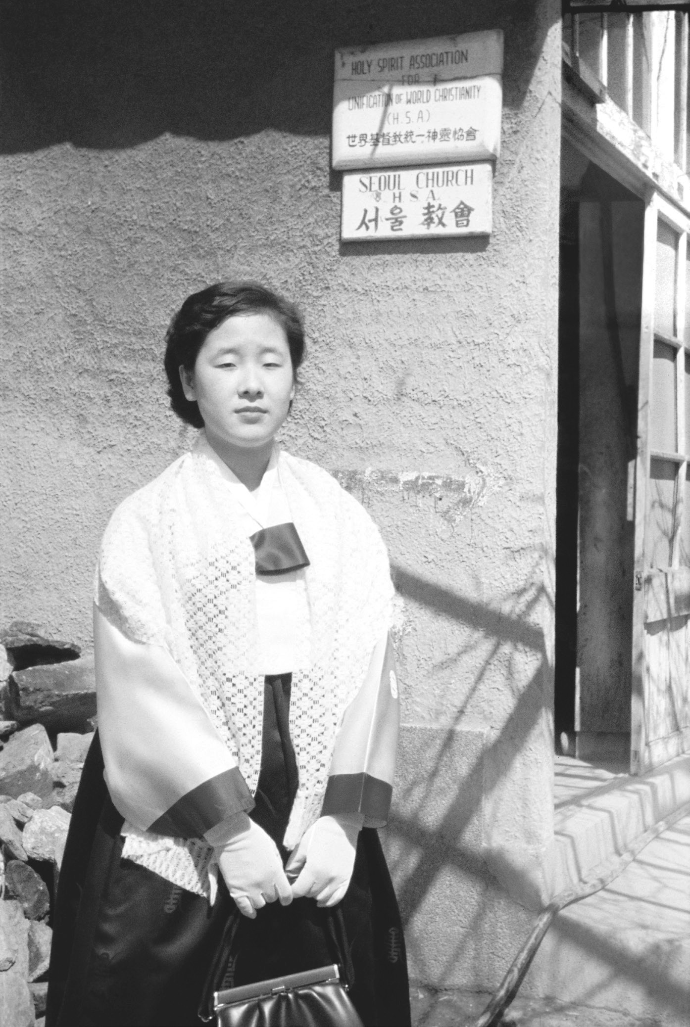 Молода дружина Мати Мун стоїть перед своїм будинком.jpg